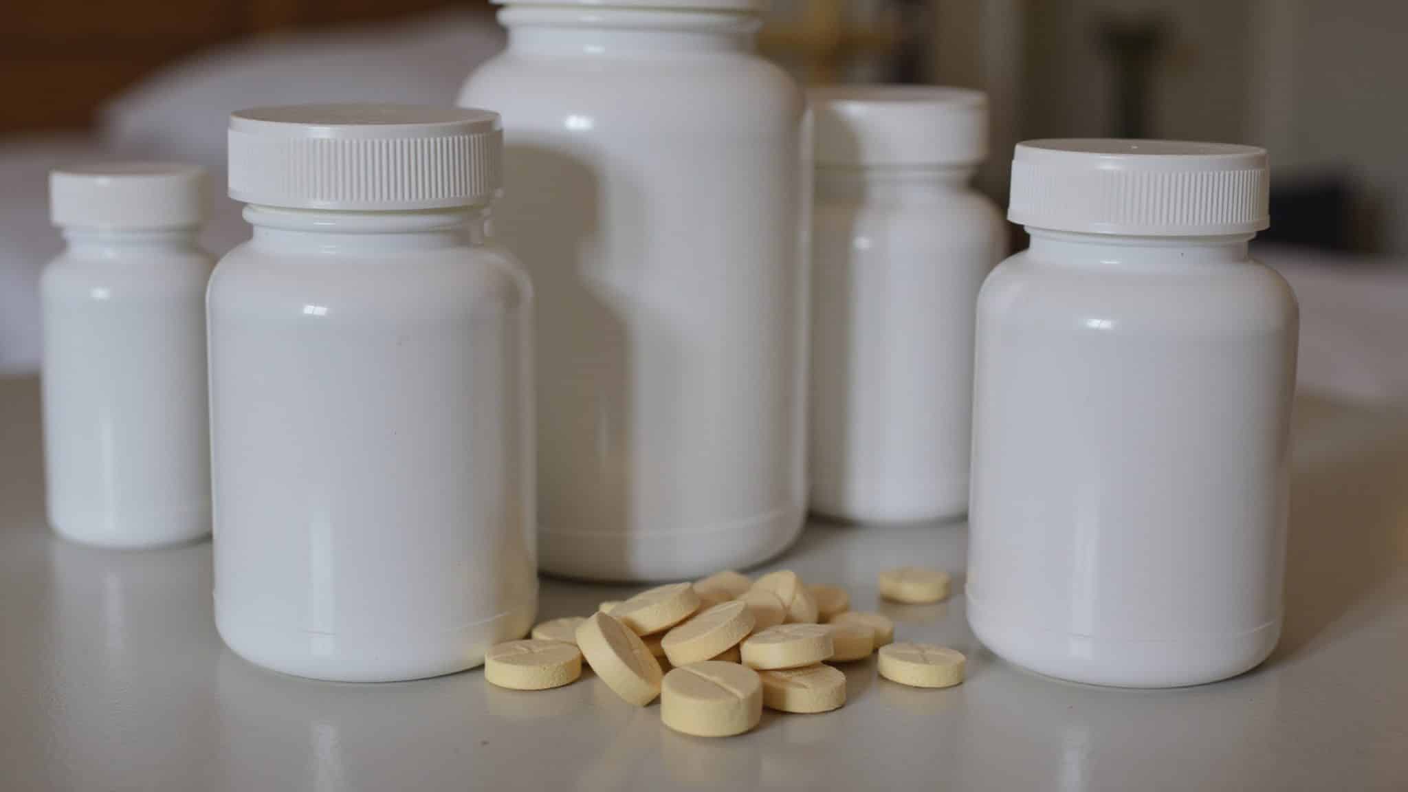 Multiple pill bottles and scattered pills on a kitchen countertop.